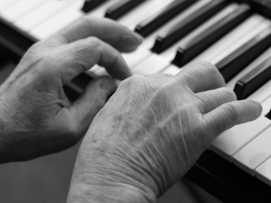 Zwei sichtbar alte Hände spielen auf einem Keyboard.